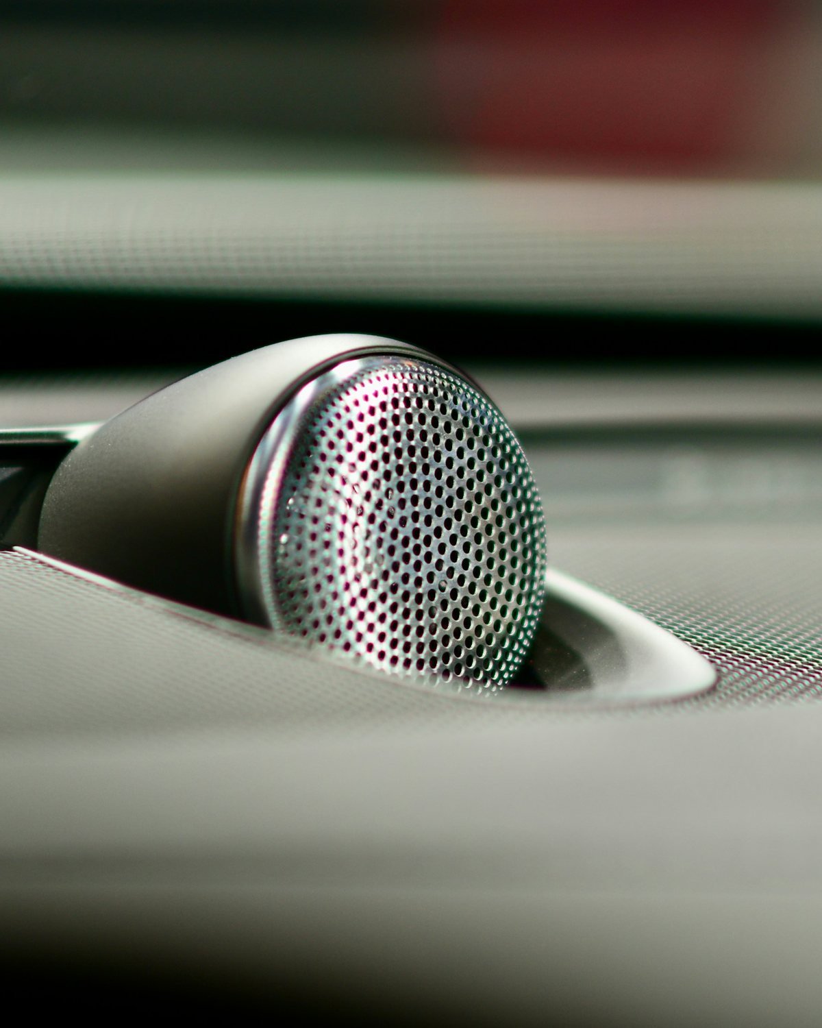 Round perforated metal tweeter speaker set into the top of a car dashboard