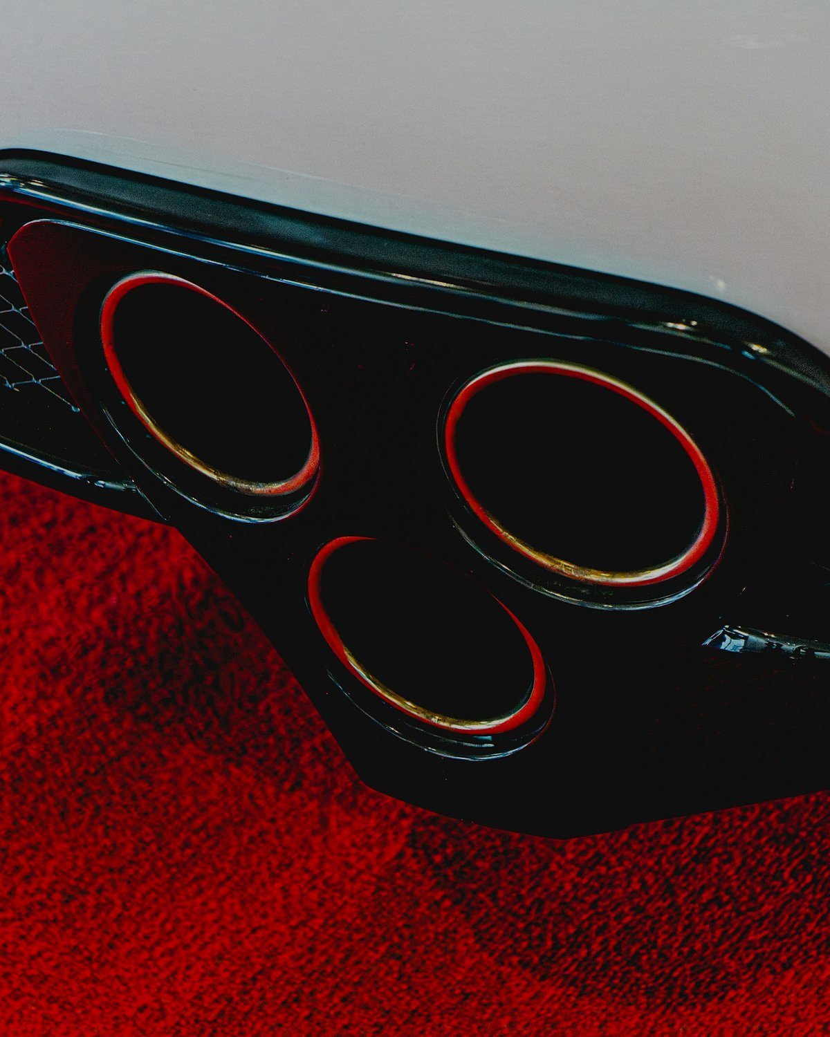 Three round exhaust tips in a gloss black rear diffuser below a white bumper