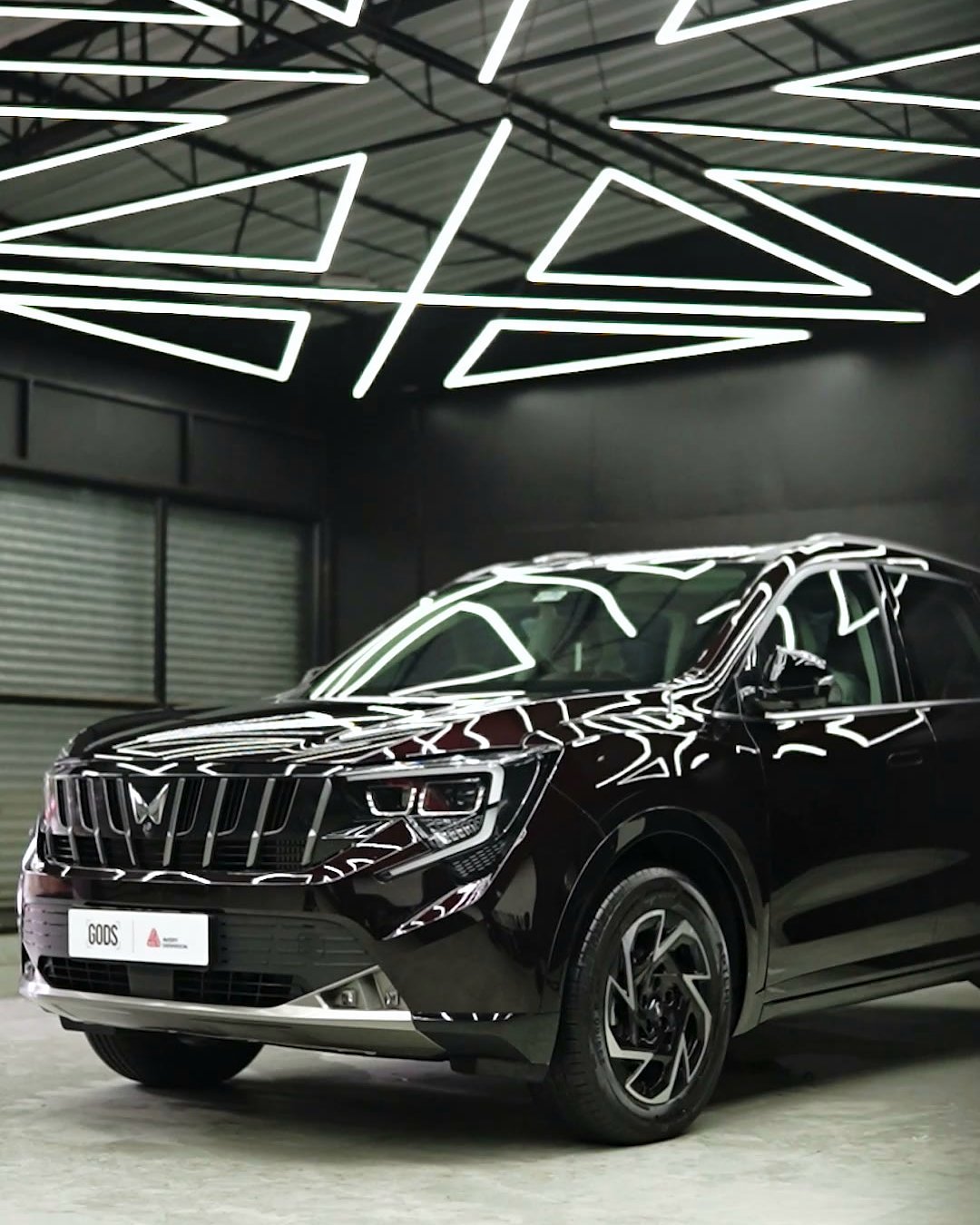 Dark Mahindra SUV under the white LED grid on the studio ceiling.