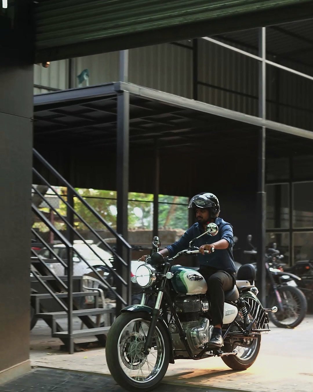 A rider coming in on a motorcycle past the stairs up to the mezzanine.